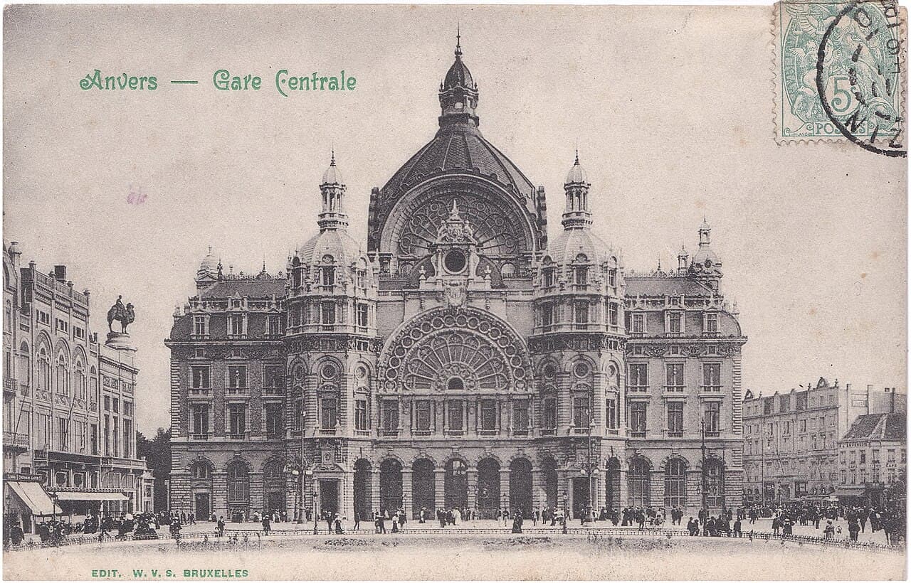 Old postcard of the domed stone façade of Antwerp Central Station, with people on the square in front